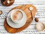 An overhead view of a cup of coffee next to bowl of sugar and a bowl of mushrooms